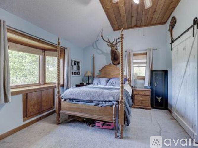A bedroom with a four poster bed and a deer head on the wall.