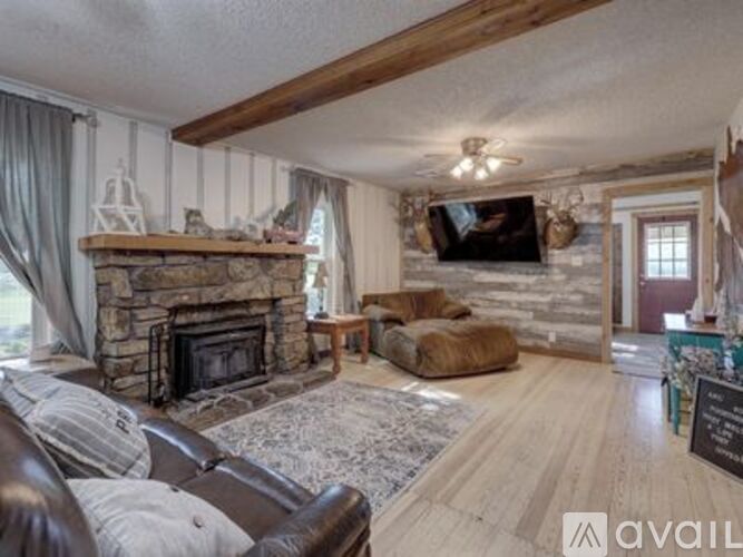 A living room with a stone fireplace and a flat screen TV mounted above it.