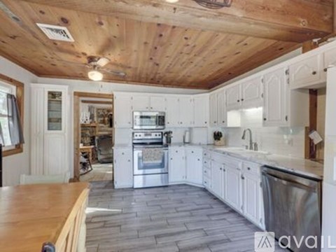 A kitchen with white cabinets and a wooden ceiling.