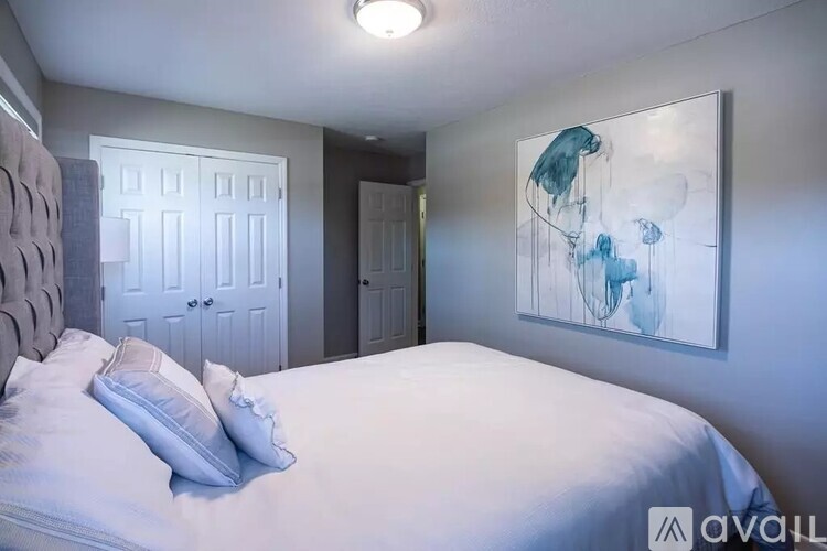 A bedroom with a large bed and a painting on the wall.