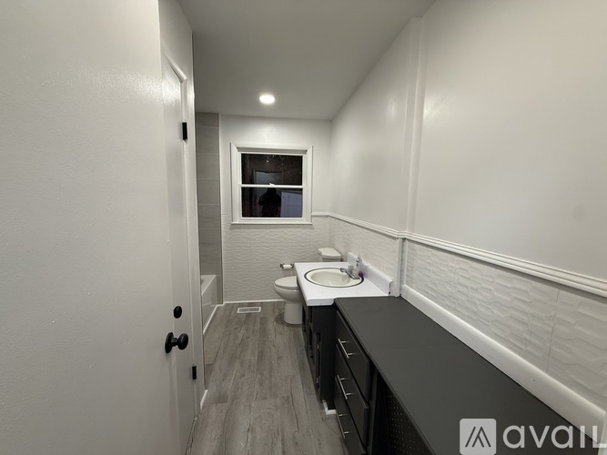 A bathroom with a toilet, sink, and a window.