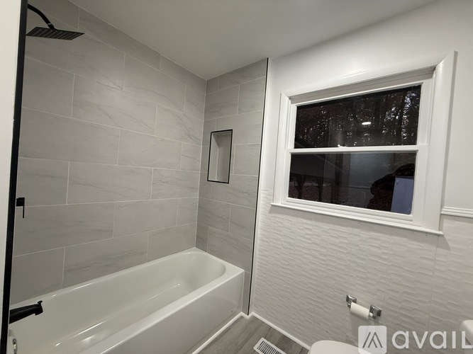 A white bathroom with a tub and a window.