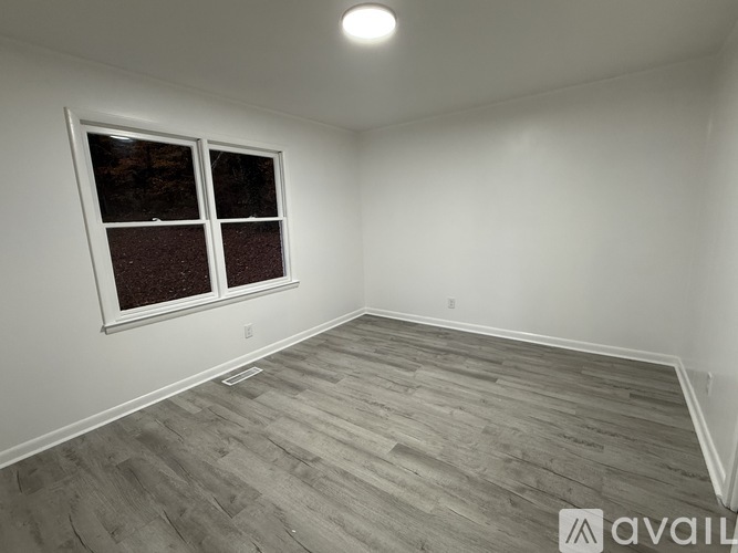 A room with a window and wooden flooring is available for rent.