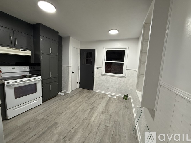 A kitchen with a white stove top oven and black cabinets.