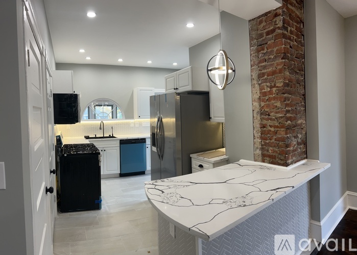A kitchen with a brick column and a marble island.