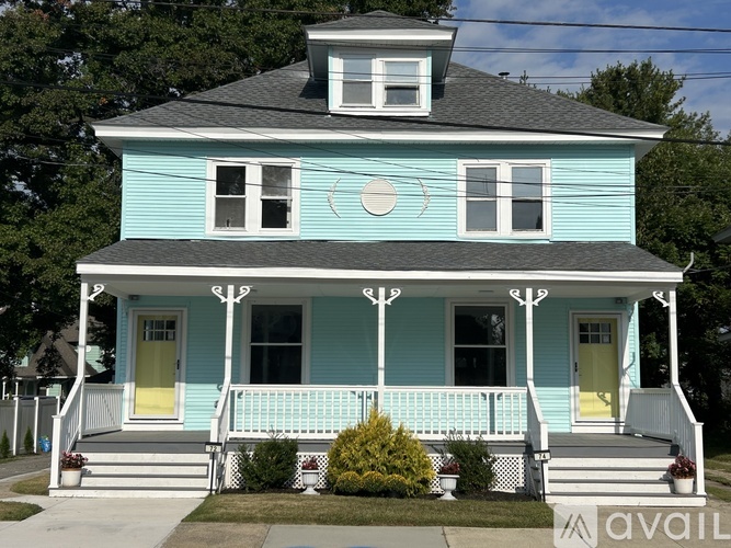 A blue house with a white porch and a yellow door.