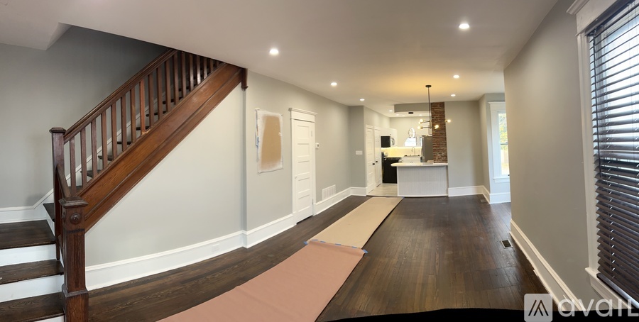 A spacious hallway with a staircase on the left and a door on the right.