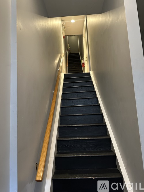 A staircase with a wooden handrail and black steps.
