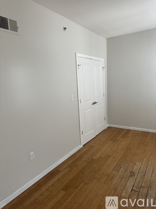 A room with a white door and wooden flooring.