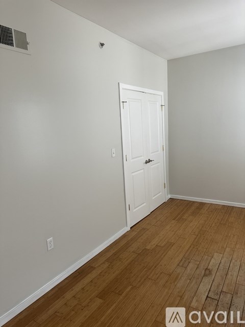 A room with a white door and wooden flooring.