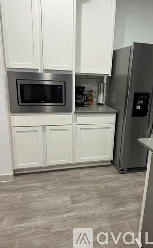 A kitchen with a refrigerator, microwave, and cabinets.
