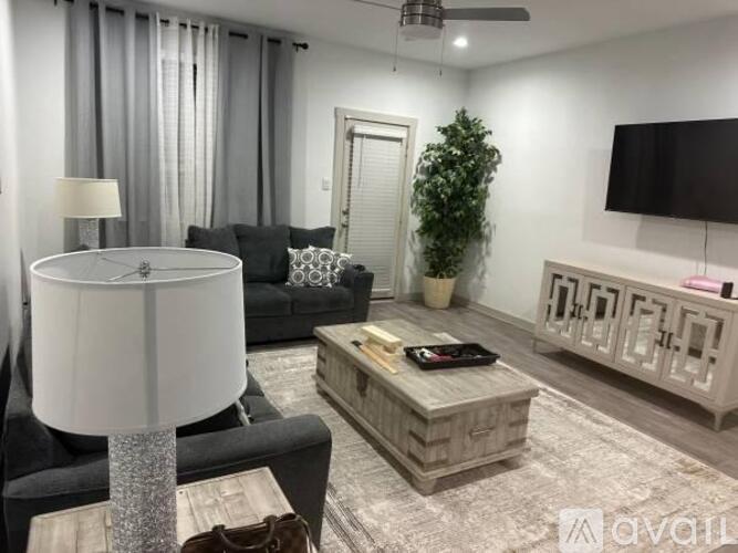 A living room with a black couch, a white floor lamp, and a wooden coffee table.