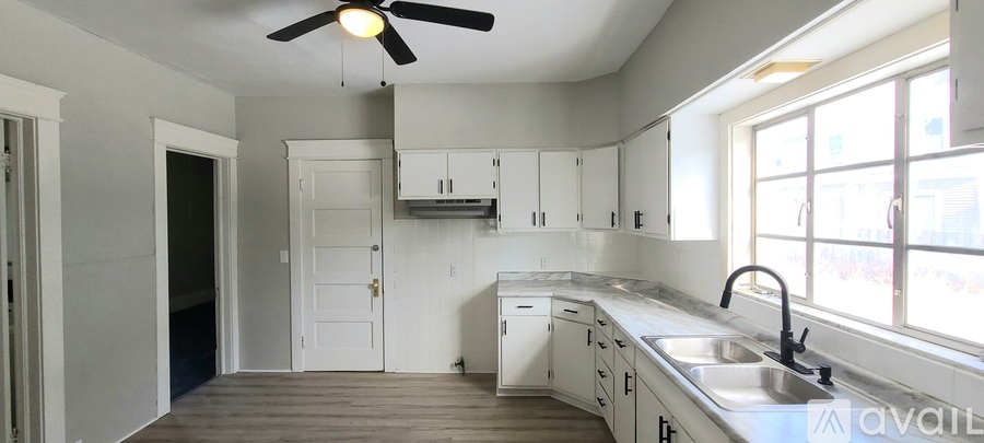 A kitchen with a sink, a window, and a ceiling fan.