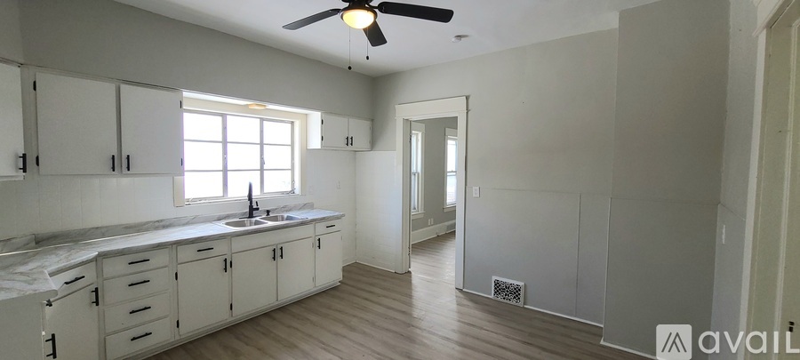 A kitchen with white cabinets and a window.