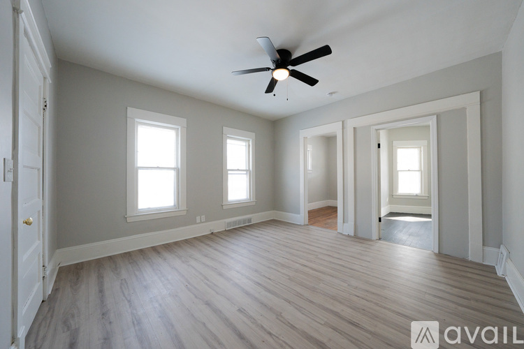 A spacious room with a ceiling fan and wooden flooring.