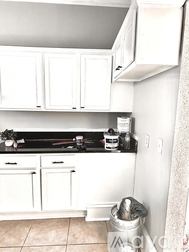 A kitchen with white cabinets and a black counter top.