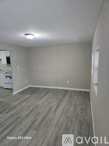 A white door is open to a room with a wooden floor.