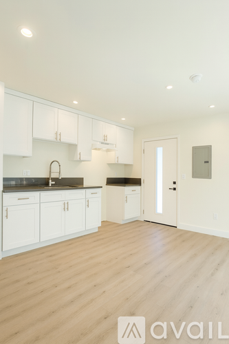 A kitchen with white cabinets and a wooden floor.