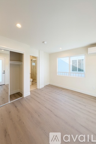 A spacious room with wooden flooring and a large mirror on the wall.