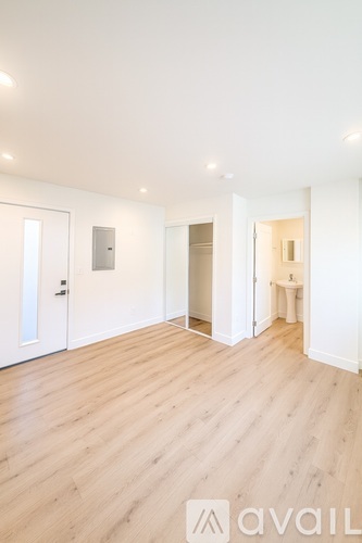 A spacious room with wooden flooring and white walls.