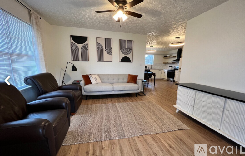 A living room with a white couch and a brown rug.