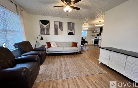 A living room with a white couch and a brown rug.