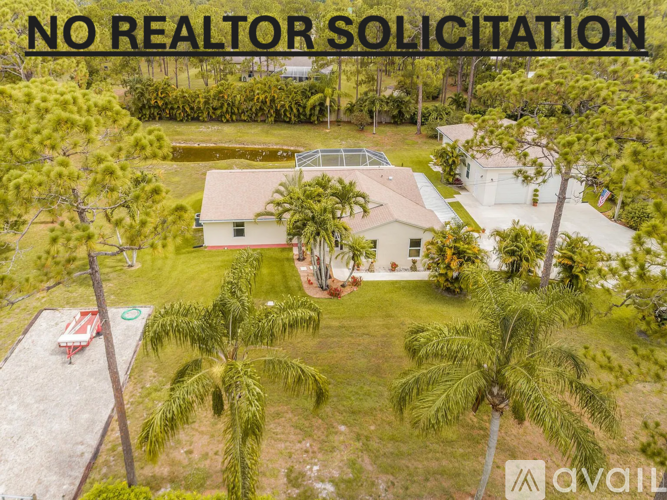 A house with a lawn and palm trees is for sale with no realtor solicitation.