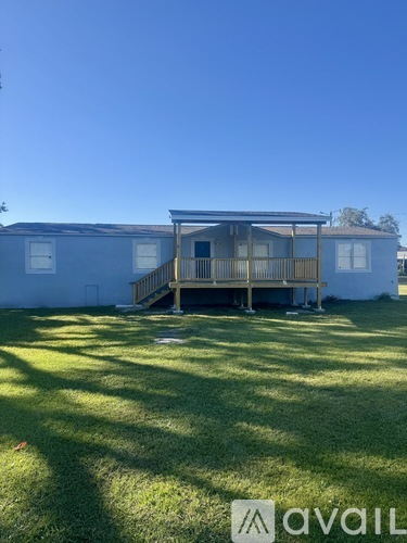 A house with a deck in the middle of a grassy area.