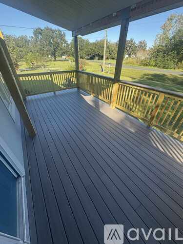A wooden deck with a railing and a view of a grassy area.