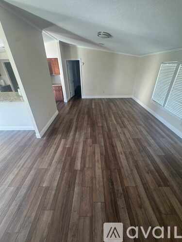 A room with wooden flooring and a door in the background.
