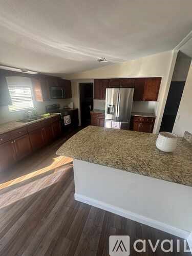 A kitchen with a granite countertop and wooden cabinets.