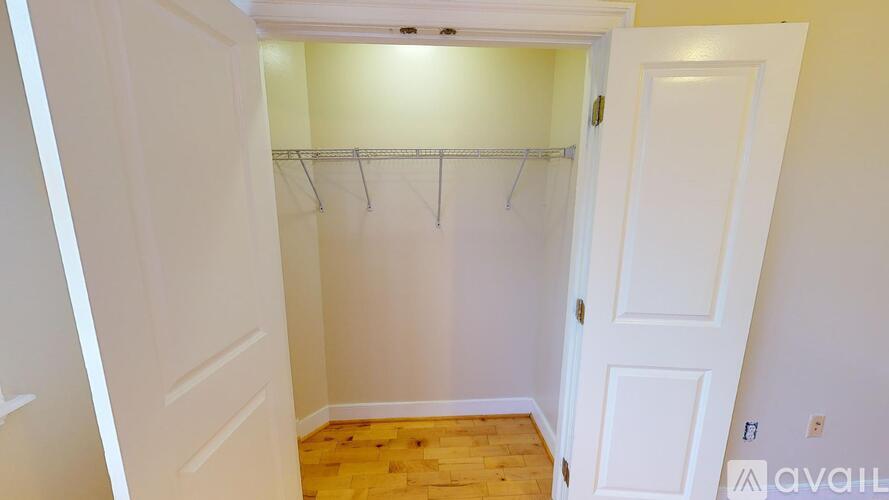 A small closet with a white door and a wooden floor.