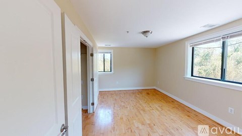A room with wooden flooring and a window overlooking trees.
