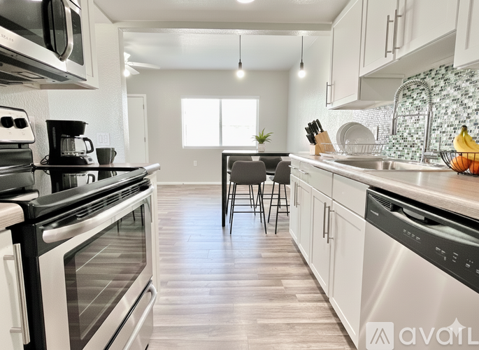 A kitchen with white cabinets and a wooden floor.