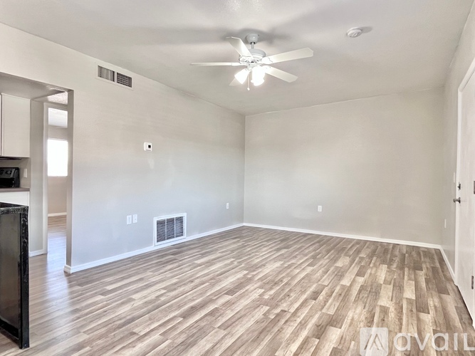 A spacious room with a ceiling fan and wood flooring.