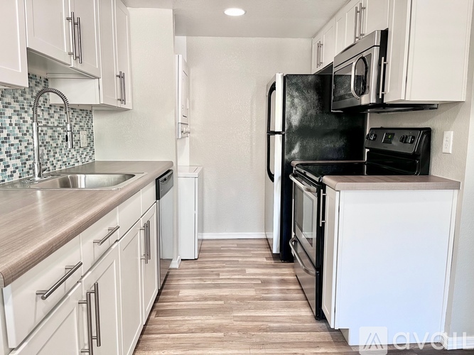 A kitchen with black appliances and white cabinets.