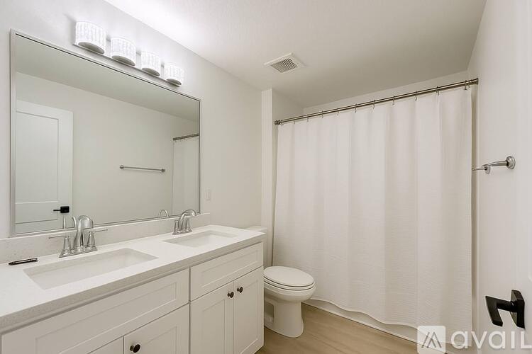 A white bathroom with a toilet, sink, and shower.