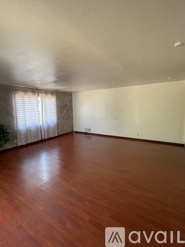 A room with wooden flooring and a window with blinds.