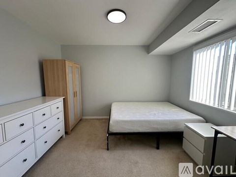 A bedroom with a bed, desk, and chair.