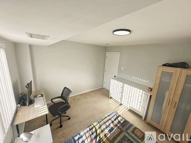 A room with a desk, chair, and a window with blinds.