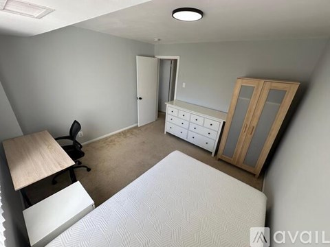 A room with a desk, chair, and a window with blinds.