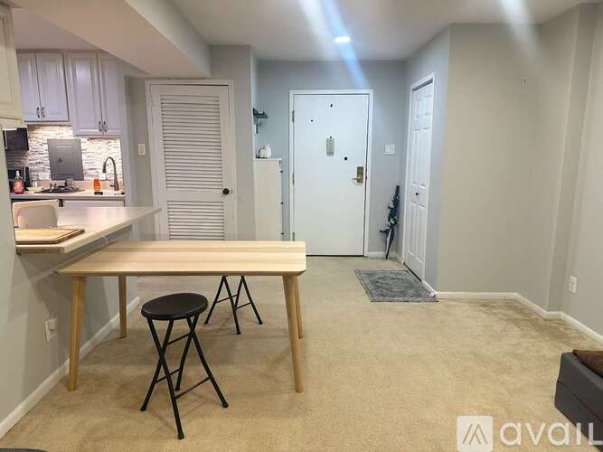 A kitchen with a table and chairs in the foreground and a hallway in the background.