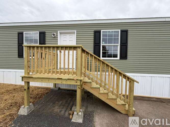 A wooden deck with a railing and steps leading to a house.