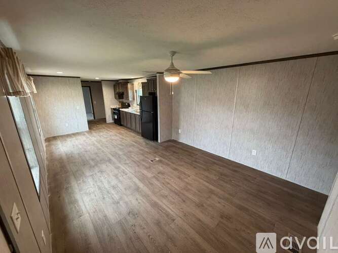 A spacious room with wooden flooring and a ceiling fan.
