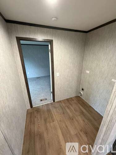 A room with wooden flooring and a door leading outside.