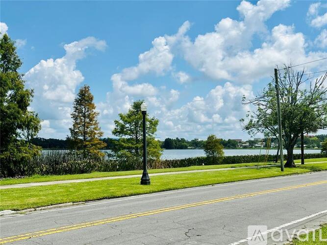 A street view with a lake and trees in the background.
