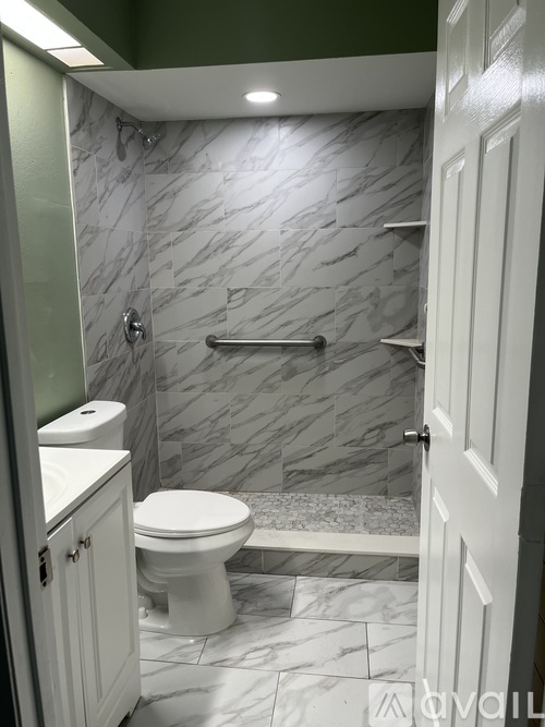 A bathroom with a toilet, sink, and marble tiles.