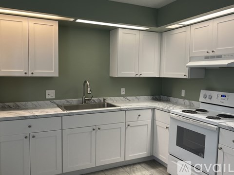 A kitchen with white cabinets and a white stove top oven.