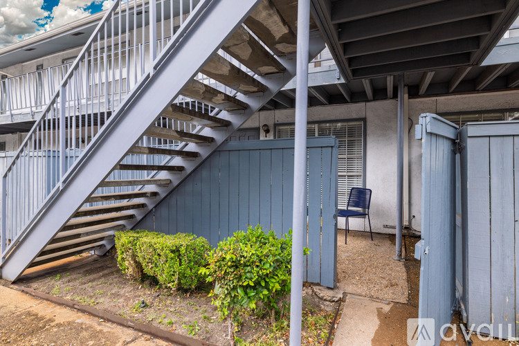A staircase with a metal railing and a blue chair under a roof.