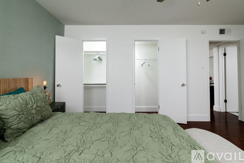 A bedroom with a bed, a nightstand with a lamp, and a closet with a mirror.